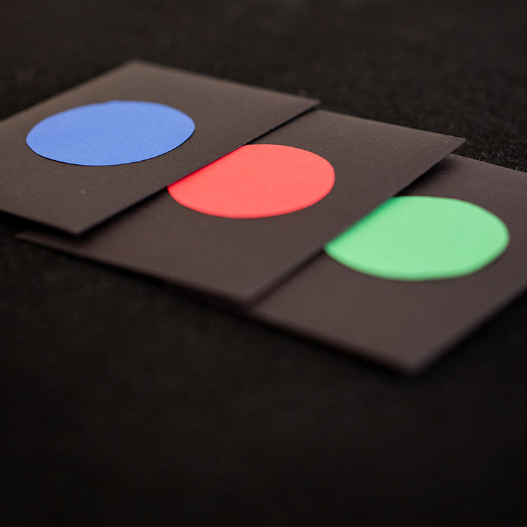 3 black envelopes with colored dots in the center of them.