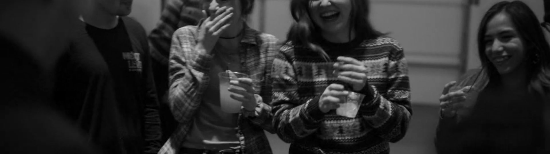 Girls holding drinks are laughing.