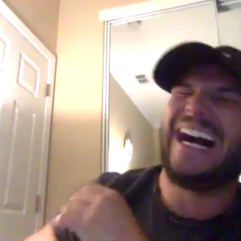 Screen shot of guy wearing a ball cap laughing.